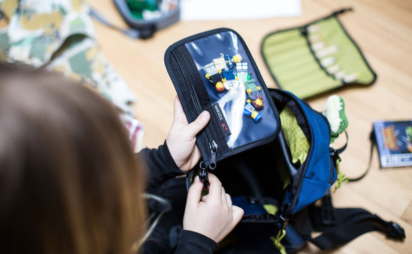 A child pulling a pouch of Legos from the main compartment of The Sprout.